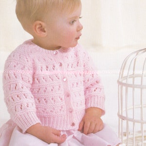 Peut inclure: Un cardigan rose en tricot pour bébé avec une fermeture boutonnée. Le cardigan présente un motif de dentelle délicat et convient à un bébé âgé de 16 à 20 pouces (41 à 51 cm).