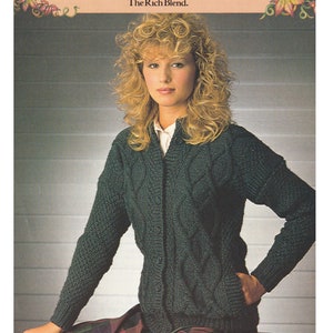 Può includere: Una donna indossa un cardigan di maglia a treccia verde scuro con bottoni. Il cardigan è realizzato con filato Patons Beehive Shetland Chunky. Il testo "The Rich Blend." è stampato sull'immagine.