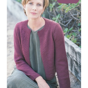 Op de afbeelding: Een vrouw draagt een kastanjebruine cardigan over een groen shirt. De cardigan is gebreid met een textuur. De tekst "Merino Aran Yarn 32 - 42 ins" is zichtbaar in de rechterbovenhoek van de afbeelding.