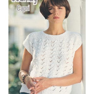 May include: A woman wearing a white, short-sleeved, knitted top with a textured pattern. The top is paired with blue denim jeans. The image includes the text "Wendy Capri" at the top.
