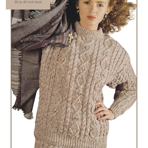 May include: A woman wearing a beige Aran knit sweater and skirt set. The sweater has a high neck and intricate cable patterns. The image includes text that reads "Aran / Worsted Yarn, Sweater and Skirt, 30 to 40 inch bust."