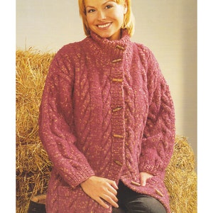 May include: A pink cable knit cardigan with wooden buttons. The cardigan is shown on a model sitting on a bale of hay. The text "Chunky / Bulky Yarn 32 - 42 ins" is visible at the top of the image.