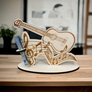 May include: Wooden music note stand with a guitar and musical notes design. The stand has a slot for holding a sheet of music.