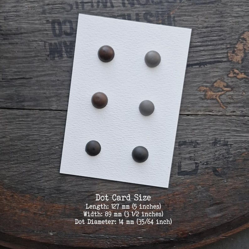 Puede incluir: Una tarjeta rectangular blanca con seis puntos circulares dispuestos en dos columnas verticales. Los puntos son de tonos marr&oacute;n, gris y negro. La tarjeta mide 127 mm de largo y 89 mm de ancho, con puntos de 14 mm de di&aacute;metro.