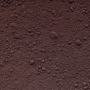 Puede incluir: Una sustancia granular de color marr&oacute;n rojizo oscuro con una textura gruesa e irregular. La superficie consta de numerosas part&iacute;culas y grumos peque&ntilde;os e irregulares, creando un aspecto denso y terroso con tonos de marr&oacute;n profundo y rojo.
