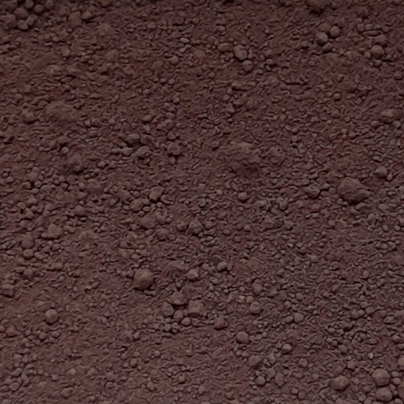 Puede incluir: Una sustancia granular de color marr&oacute;n rojizo oscuro con una textura gruesa e irregular. La superficie consta de numerosas part&iacute;culas y grumos peque&ntilde;os e irregulares, creando un aspecto denso y terroso con tonos de marr&oacute;n profundo y rojo.