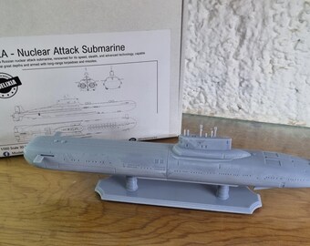 Könnte beinhalten: Graues Kunststoffmodell eines Akula-Atomangriff-U-Boots, mit der Schachtel im Hintergrund. Auf der Schachtel steht "AKULA - Nuclear Attack Submarine" und eine Zeichnung des U-Boots. Das Modell steht auf einem grauen Ständer.