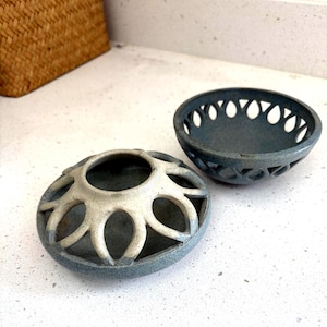May include: Two ceramic bowls with a blue-grey speckled glaze and openwork cutouts along the rims. One bowl features a white-glazed top section with petal-shaped openings, while the other is a solid blue-grey bowl with a row of teardrop cutouts.