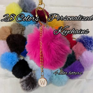 May include: A collection of colorful, fluffy keychains in various shades, including pink, blue, and yellow. The keychains are personalized with a letter charm and a gold chain. Text on the image reads "28 Colors Personalized Keychains" and "4 color letters."