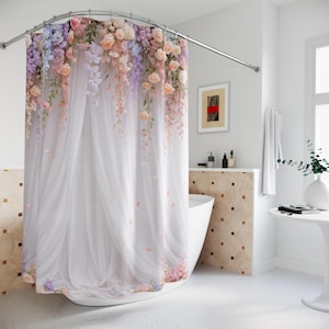 May include: A floral shower curtain with a white sheer fabric design. The curtain features cascading flowers in shades of pink, peach, lavender, and white. The shower curtain is hanging from a curved, silver-colored shower rod.