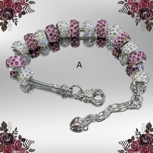 May include: A silver bracelet with a variety of decorative beads. The beads are a mix of silver and purple, some encrusted with clear crystals. The bracelet has a clasp closure and a chain extension.