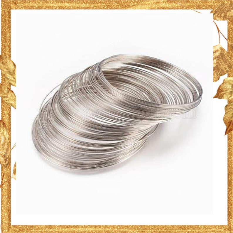 May include: A stack of multiple thin, circular silver-toned metal wire bangles. The bracelets are constructed from a single continuous strand of coiled wire, creating a layered, flexible, and lightweight appearance with a smooth, reflective finish.