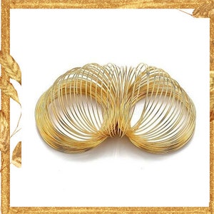 May include: A gold-colored metal spring toy featuring a continuous coiled wire design. The object is composed of numerous circular loops that form a flexible, expandable structure with a metallic finish and a reflective, shiny surface texture.