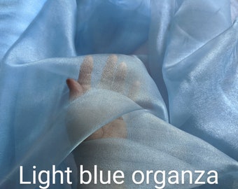 May include: Light blue sheer organza fabric. The fabric is soft and delicate, with a slight sheen.
