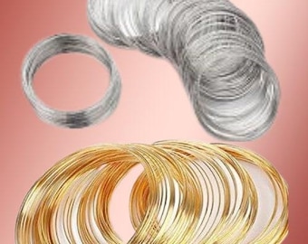 May include: A collection of circular wire coils in silver and gold tones. The silver wire is arranged in a single loop and a larger stacked bundle, while the gold wire is organized into a wide, overlapping cluster of multiple circular loops.