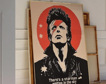 May include: A black and white poster featuring a portrait of David Bowie with a red circle behind him. The text on the poster reads "There's a starman waiting in the sky."