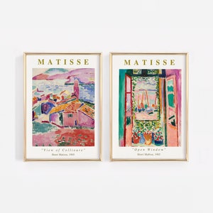 Puede incluir: Dos impresiones de arte enmarcadas de pinturas de Henri Matisse. La primera impresi&oacute;n se titula "Vista de Collioure" y representa un paisaje colorido con una ciudad y el mar. La segunda impresi&oacute;n se titula "Ventana abierta" y muestra una vista de un puerto a trav&eacute;s de una ventana abierta.