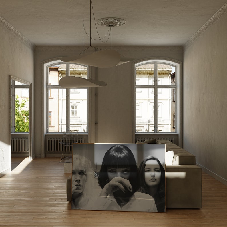 May include: A black and white photograph of three women, framed and hanging on a wall in a living room. The women are looking at the camera with serious expressions. The room is decorated in a minimalist style with white walls and a large window.