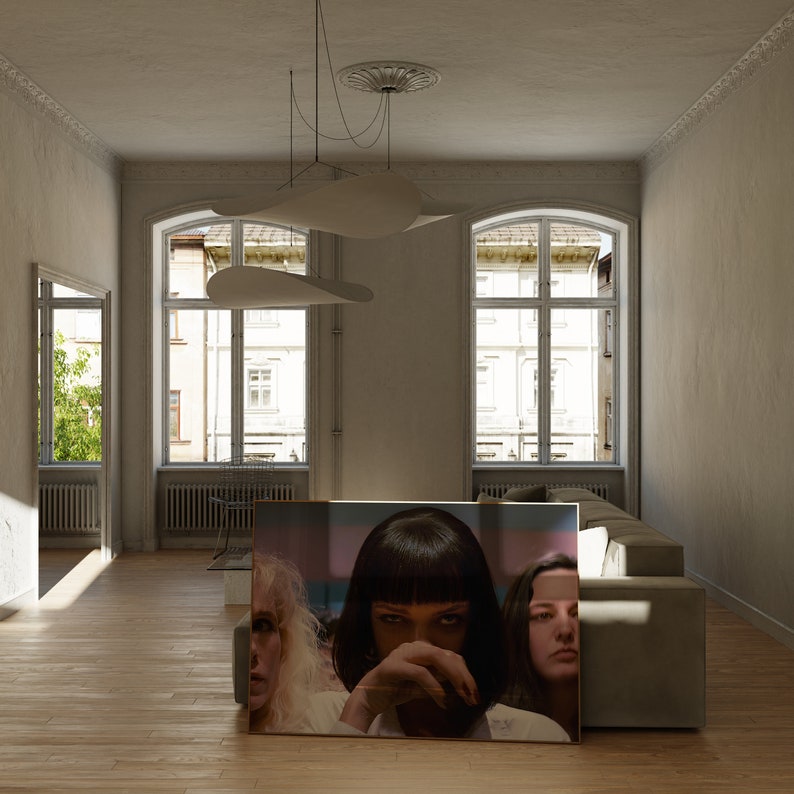 May include: A large framed poster with a scene from a movie. Three women are featured in the poster. The woman in the center is wearing a black wig and a black top. The woman on the left is wearing a white shirt and the woman on the right is wearing a black shirt. The poster is hanging on a wall in a living room.