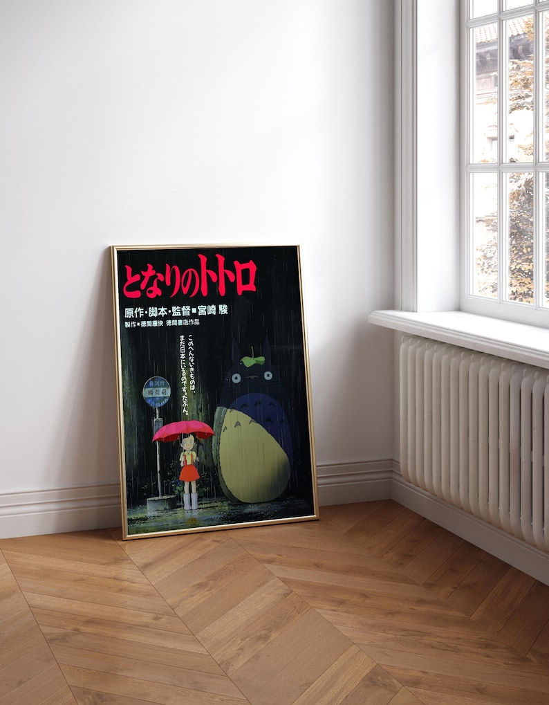 May include: Framed poster featuring the Japanese animated film "My Neighbor Totoro." The artwork depicts a young girl with a red umbrella standing at a bus stop with Totoro. The poster has Japanese text in red and gold tones.