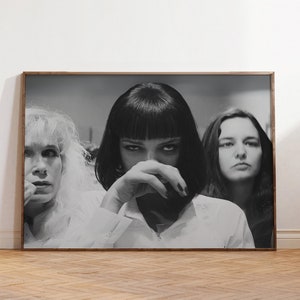 May include: Black and white photograph of three women. The woman in the center is wearing a white shirt and has her hand covering her mouth. The woman on the left is wearing a white shirt and has her hair pulled back. The woman on the right is wearing a white shirt and has her hair down.