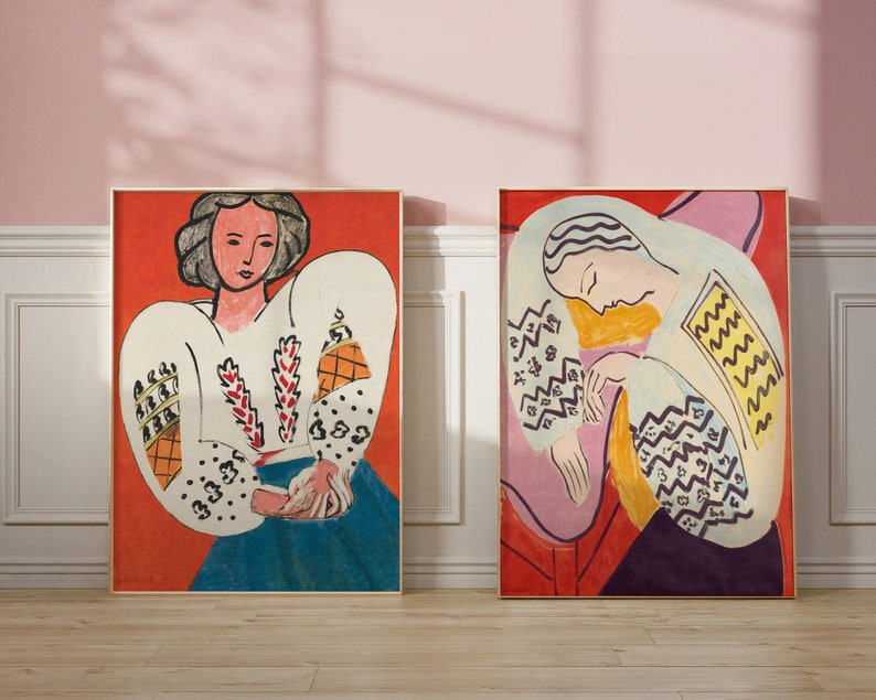 May include: Two framed paintings of women with colorful patterns on their clothing. The woman on the left is wearing a white blouse with red and yellow patterns. The woman on the right is wearing a white blouse with yellow and blue patterns. Both paintings have a red background.