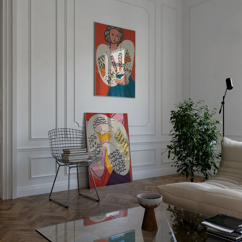 May include: Two framed abstract paintings with colorful geometric patterns and figures. The paintings are hanging on a white wall in a room with a wooden floor.