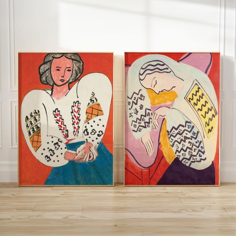 May include: Two framed paintings of women in white blouses with colorful geometric patterns. The paintings are set against a red background.