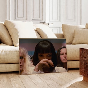 May include: A framed movie poster featuring three women. The woman in the center has dark hair and is looking directly at the viewer. The woman on the left has blonde hair and is looking to the right. The woman on the right has dark hair and is looking to the left.