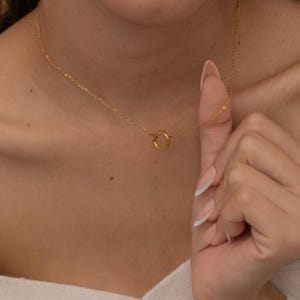 May include: A gold chain necklace with a simple circle pendant.