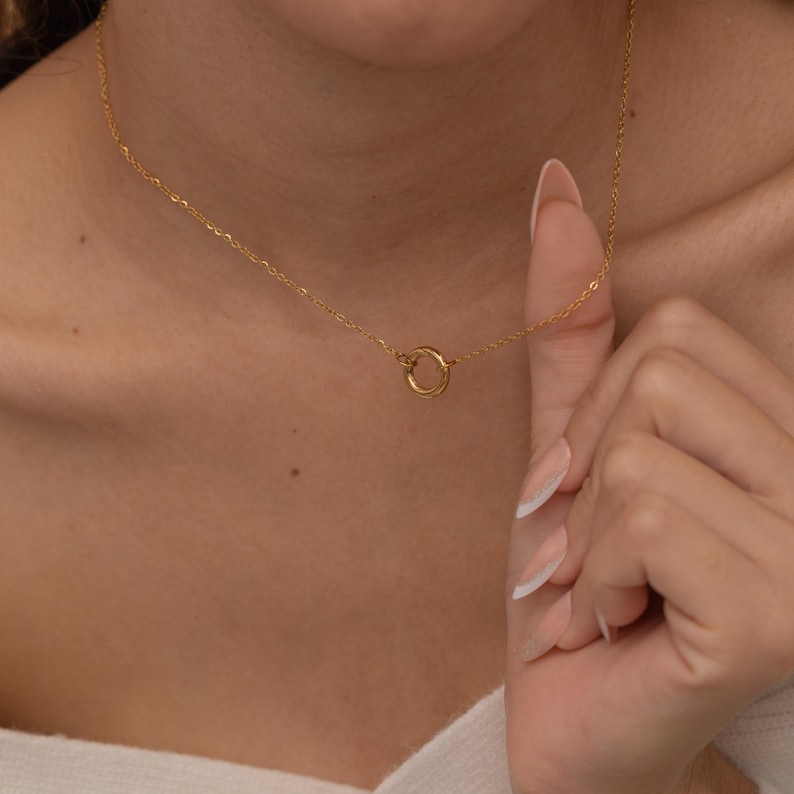 May include: A gold chain necklace with a simple circle pendant.