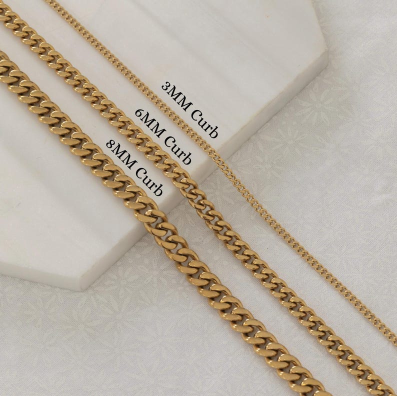 May include: Gold-colored curb chain necklaces in 3mm, 6mm, and 8mm widths. The chains are displayed on a white surface. Text labels identify each chain size. The chains are a shiny gold color.
