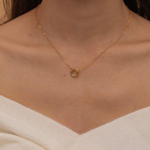 May include: A gold chain necklace with a simple circle pendant.