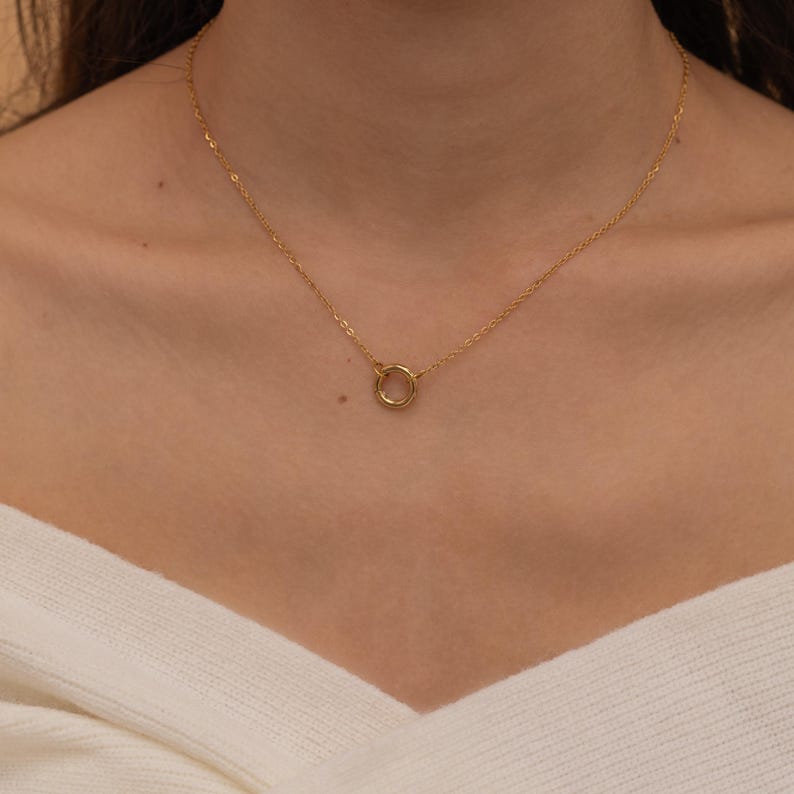 May include: A gold chain necklace with a simple circle pendant.