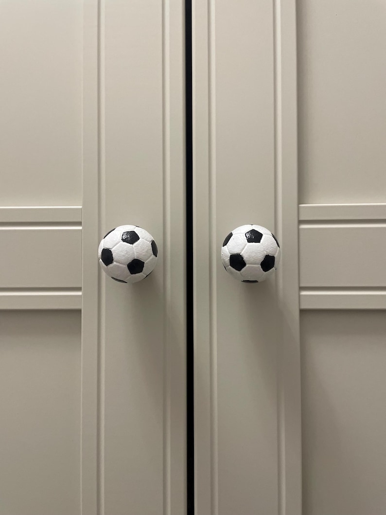 May include: Two white cabinet doors with black soccer ball shaped door knobs.
