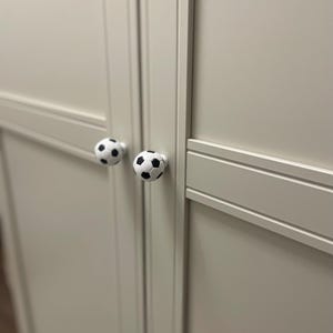 May include: Two white cabinet doors with black soccer ball-shaped knobs.