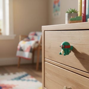 K&ouml;nnte beinhalten: Eine Kommode aus hellem Holz mit zwei Schubladen, verziert mit einem gr&uuml;nen und roten Cartoon-Knauf. Der Raum hat ein Fenster, einen Stuhl mit einer gemusterten Decke und einen Teppich.