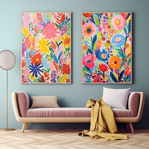 Può includere: Due stampe artistiche floreali incorniciate con colori vivaci, tra cui fiori rosa, gialli, blu e arancioni. L'opera d'arte è appesa sopra una chaise longue rosa con una coperta gialla e un cuscino bianco. Una lampada da terra è a sinistra.