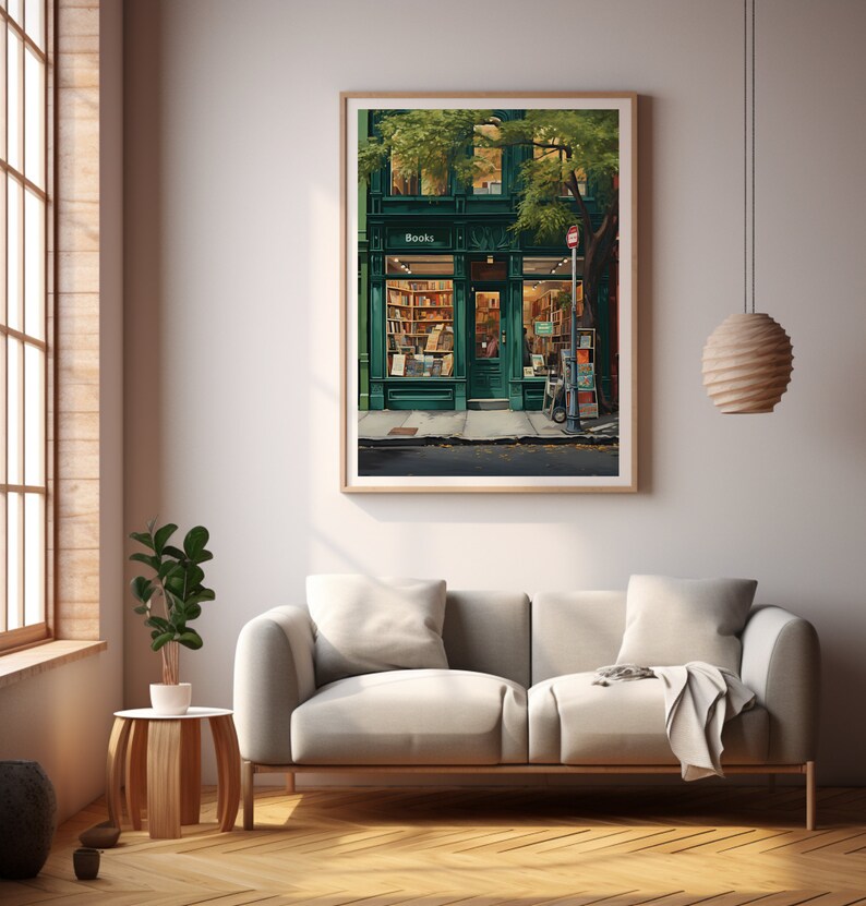 May include: A framed print depicting a charming bookstore with a green exterior and the word "Books" above the door. The interior is illuminated, revealing bookshelves filled with books. The artwork hangs above a light grey sofa in a bright room.