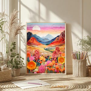 Pu&ograve; includere: Una stampa artistica incorniciata con un paesaggio vibrante con un tramonto colorato, montagne e un campo di fiori. L'opera d'arte utilizza una tavolozza di rosa, arancioni, blu e gialli. La stampa &egrave; esposta su un tappeto con matite e un blocco per disegnare nelle vicinanze.