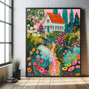 May include: A framed art print showing a vibrant garden scene with a light blue house, an orange roof, and a winding path. The garden is filled with flowers in shades of pink, yellow, and white, set against a pink sky. The artwork is framed in black.