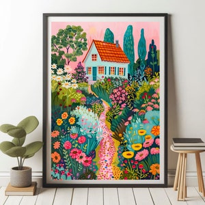 May include: A framed art print showing a garden path leading to a small house. The house has a red tile roof and blue shutters. The garden is filled with pink, yellow, and orange flowers, with green foliage and trees. The sky is a soft pink, creating a vibrant scene.