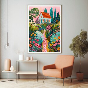 May include: A framed art print showing a garden scene with a small house. The house has a red roof and blue walls, surrounded by colourful flowers and trees. A stone path leads through the garden, creating a whimsical and inviting atmosphere.