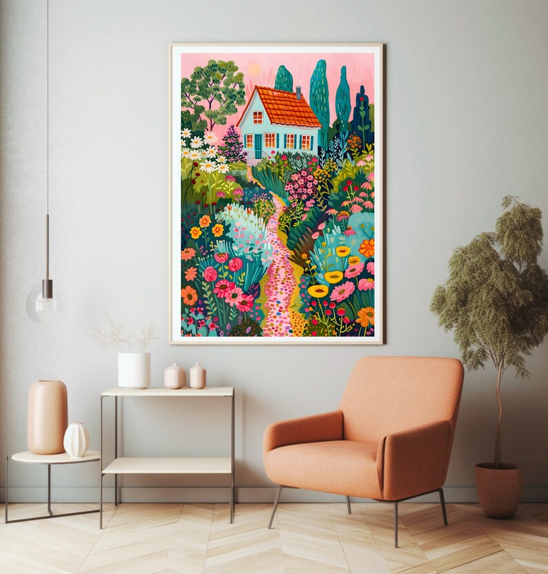 May include: A framed art print showing a garden scene with a small house. The house has a red roof and blue walls, surrounded by colourful flowers and trees. A stone path leads through the garden, creating a whimsical and inviting atmosphere.