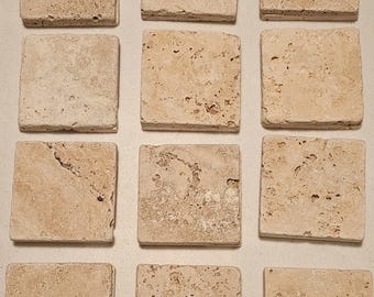 May include: Twelve square beige travertine tiles with a rough, textured surface.