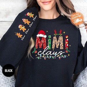 以下が含まれることがあります： クリスマスをテーマにしたデザインの黒いスウェットシャツ。カラフルな文字で「Mimi Claus」と書いてあり、ジンジャーブレッドマンとライトが描かれています。デザインには、レオパード柄、水玉模様、キャンディーケーンのストライプが含まれています。