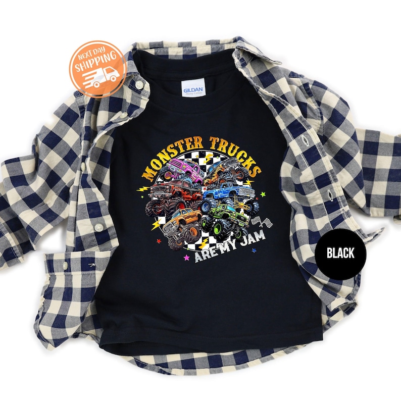 Puede incluir: Camiseta negra con un gr&aacute;fico colorido de monster trucks. El dise&ntilde;o incluye el texto "MONSTER TRUCKS ARE MY JAM" en amarillo y blanco. Una camisa a cuadros azul y blanca est&aacute; superpuesta.