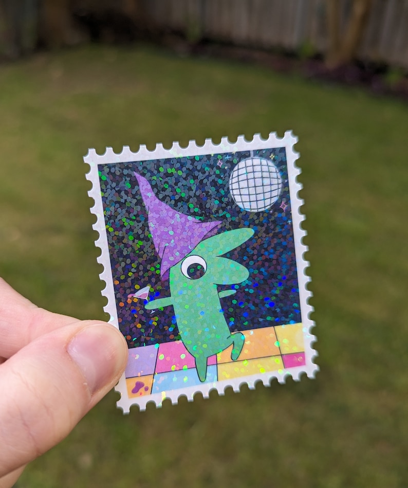 May include: A green cartoon character wearing a purple hat dances on a glittery dance floor with a disco ball in the background. The character is holding a martini glass. The image is printed on a holographic sticker.