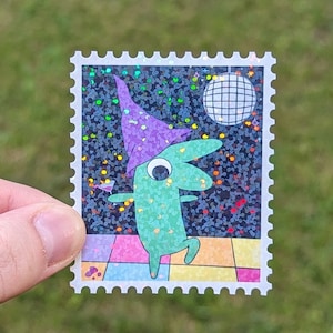 May include: A green creature wearing a purple hat dances on a glittery black background with a disco ball. The creature is holding a martini glass. The image is printed on a white sticker with a postage stamp border.