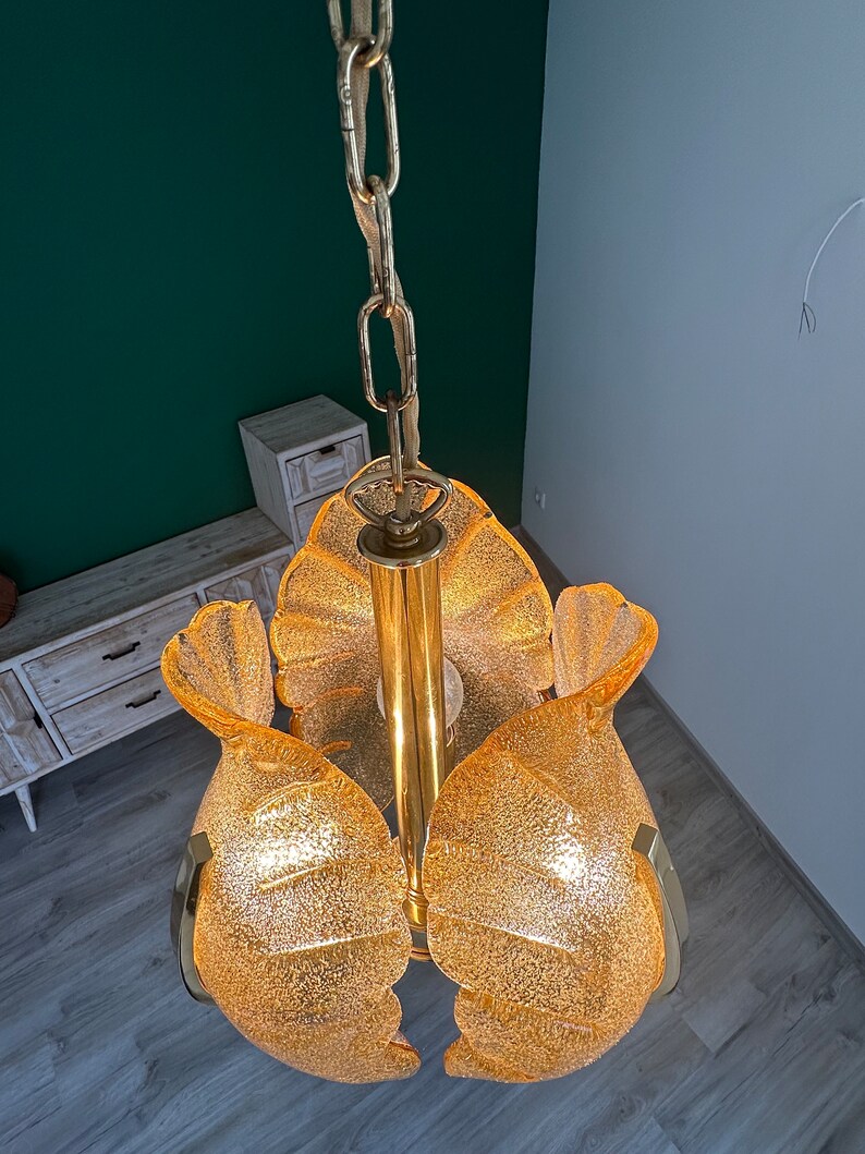 May include: A gold-toned chandelier with a chain and five frosted glass flower-shaped shades.